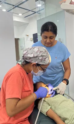 Dr. Puja Bansal and an assistant performing a dental procedure